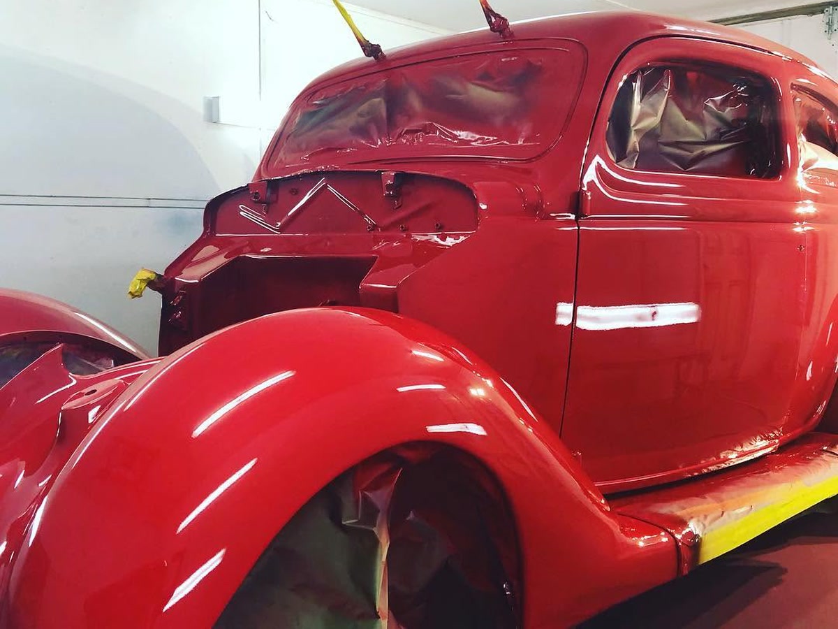 A classic Ford coupe in fresh red paint in the booth at Superior Collision in Brownsville, TX