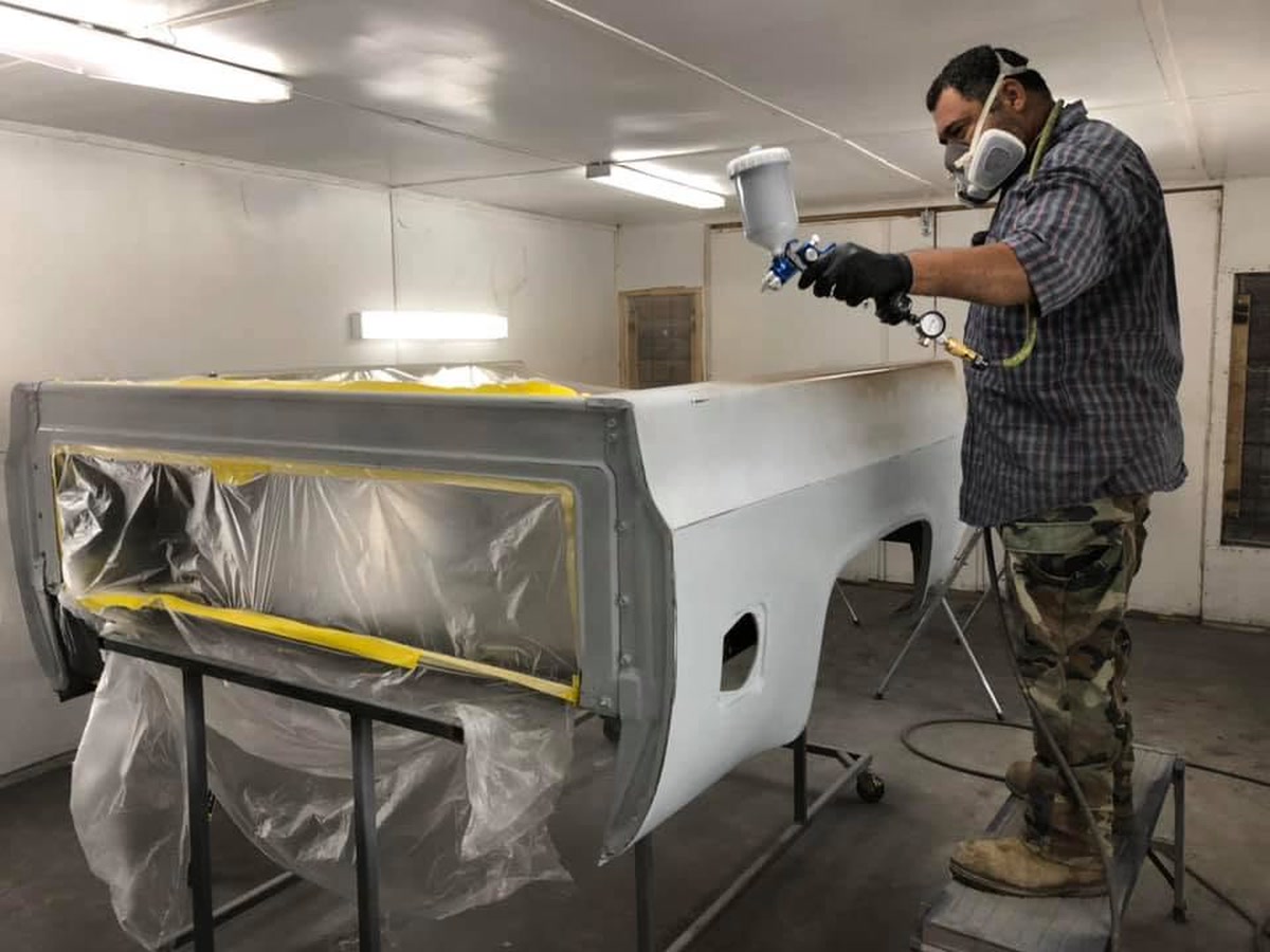 A Superior Collision painter refinishing a truck bed in the paint booth in Brownsville, TX